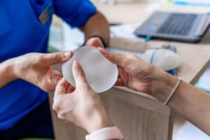 Woman examines a breast implant with a medical professional ahead of her breast augmentation surgery